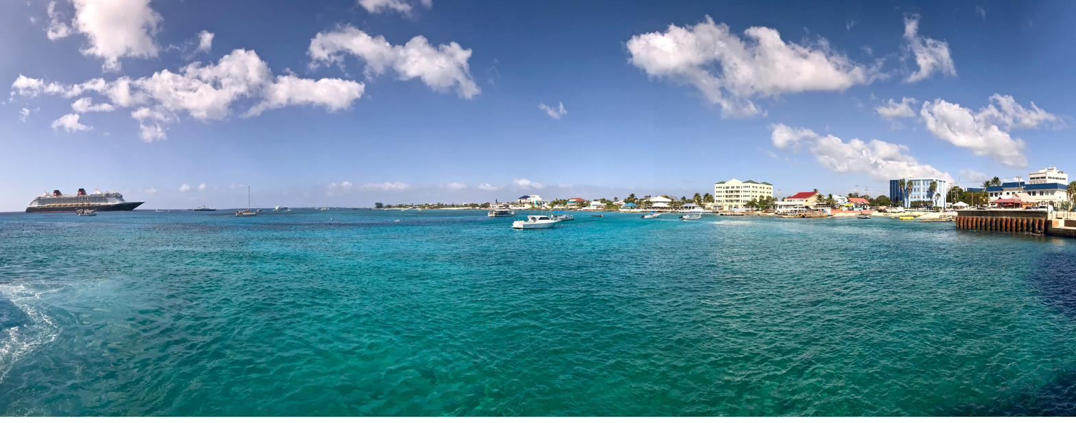 George Town harbour on Grand Cayman, with the waterfront, moored boats and a cruise ship under a bright sky